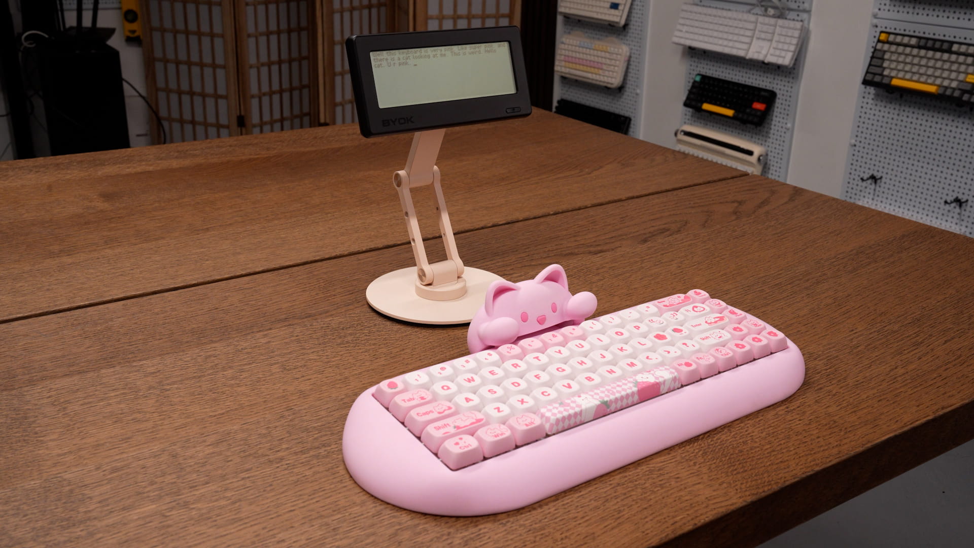 BYOK on a pink desk stand behind a pink mechanical keyboard