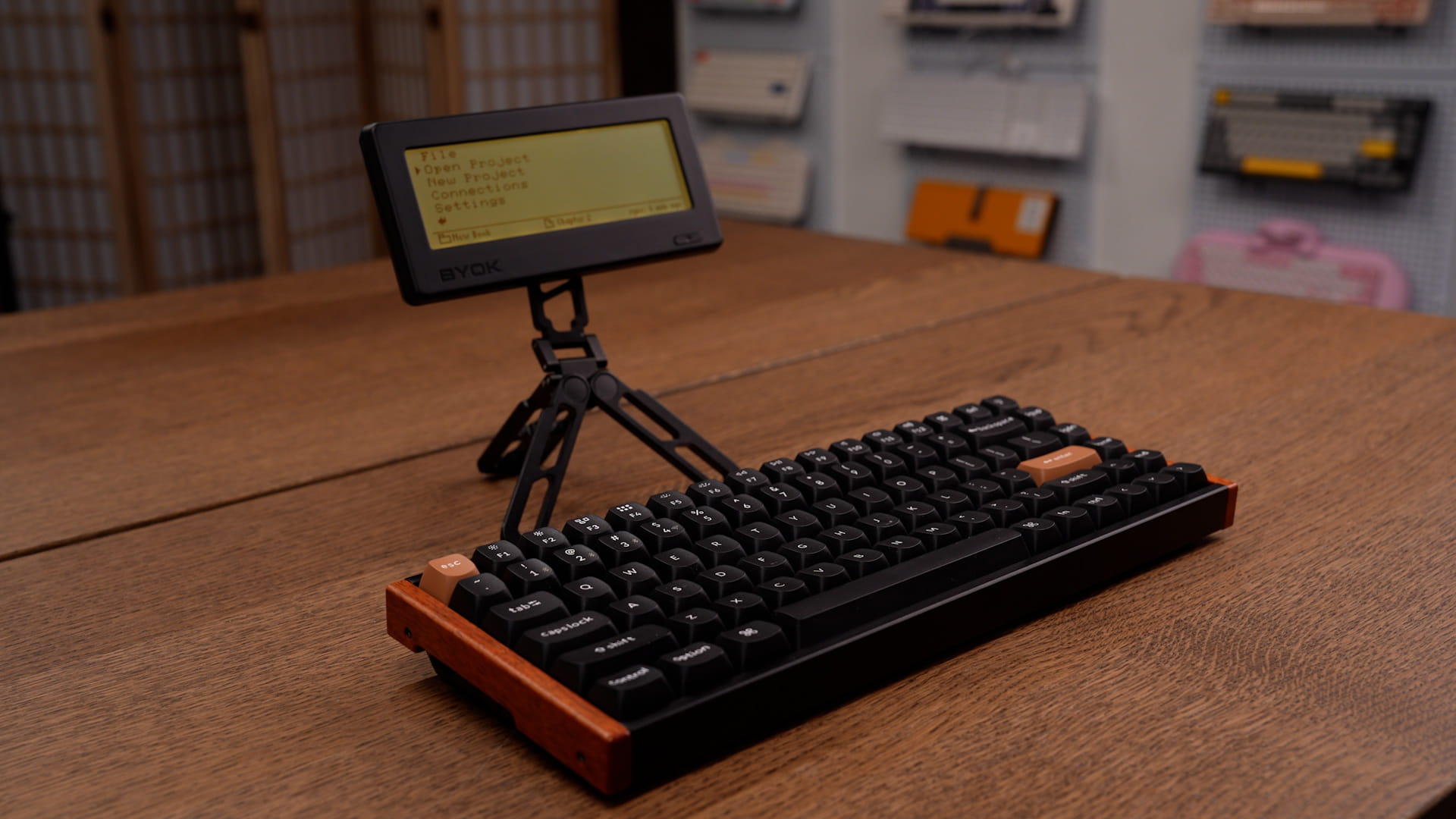BYOK on a compact folding tripod stand behind a Keychron K2 HE Special Edition keyboard