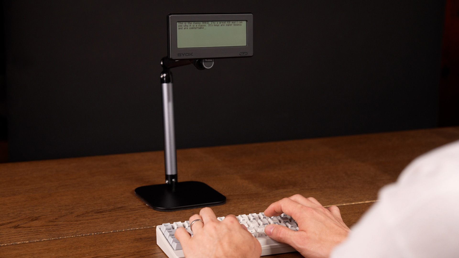 BYOK raised to eye level on a tall desk stand above an HHKB keyboard