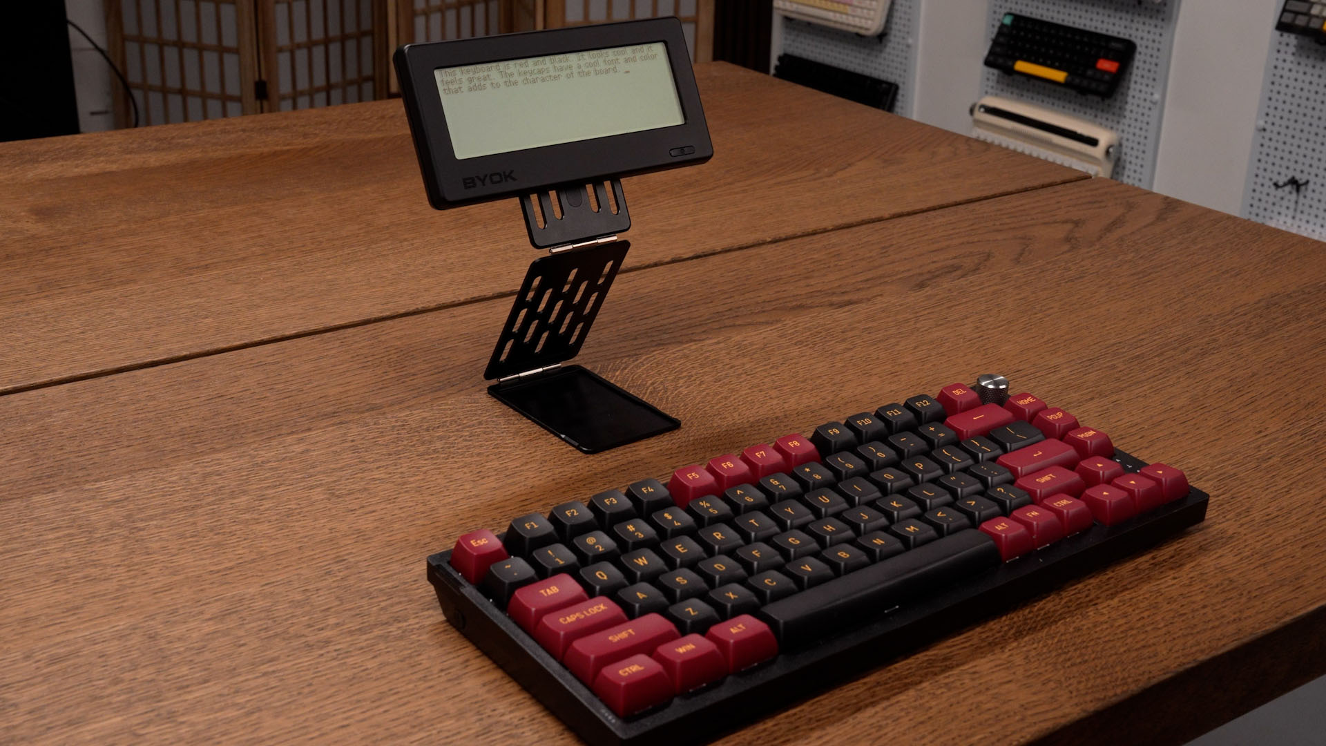 BYOK raised on a credit-card-sized folding stand behind a mechanical keyboard